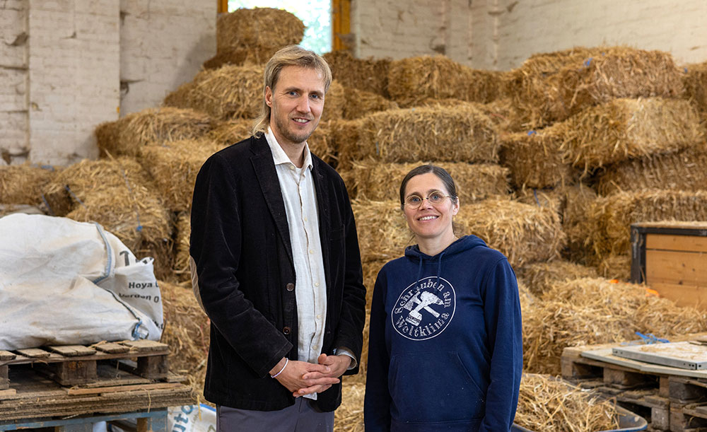Ein Mann und eine Frau in einem Stall voller Strohballen